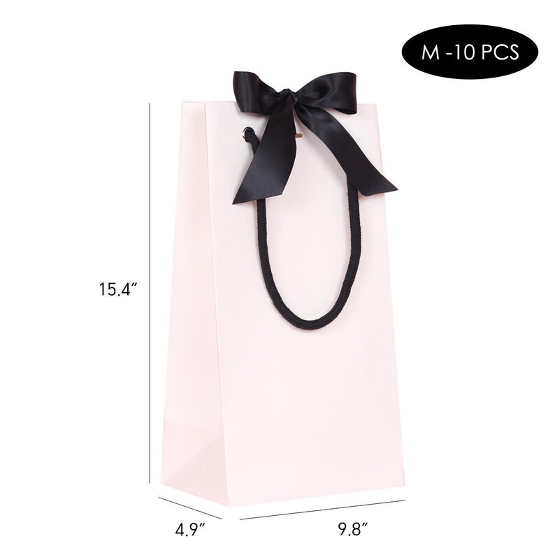 May include: A light pink gift bag with a black satin bow and black rope handles. The bag is 15.4 inches tall, 9.8 inches wide, and 4.9 inches deep. The text "M - 10 PCS" is in a black oval.