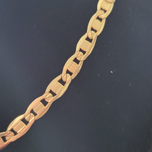 Op de afbeelding: Een gouden ketting met een ankerketting ontwerp. De ketting is gemaakt van massief goud en heeft een gepolijste afwerking.