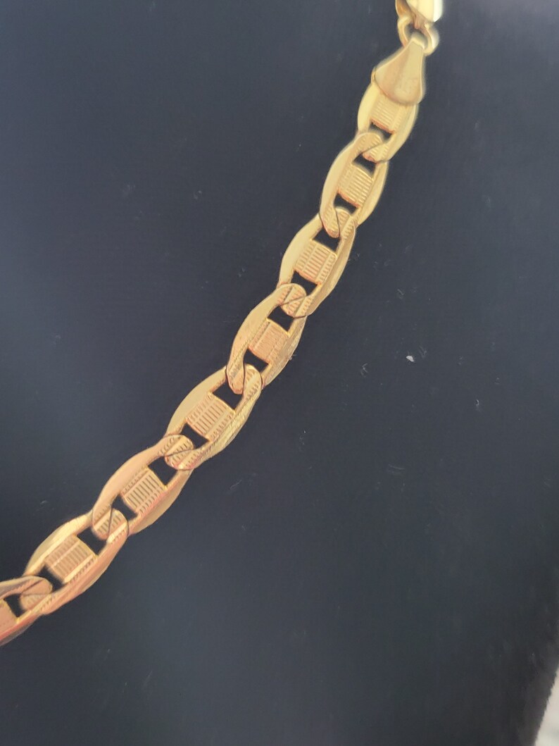 Op de afbeelding: Een gouden ketting met een ankerketting ontwerp. De ketting is gemaakt van massief goud en heeft een gepolijste afwerking.