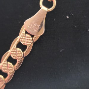 Op de afbeelding: Close-up van een gouden kettinghalsband sluiting met de inscriptie "14K ITALY" op de achterkant.
