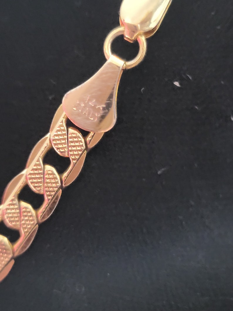 Op de afbeelding: Close-up van een gouden kettinghalsband sluiting met de inscriptie "14K ITALY" op de achterkant.