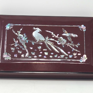 May include: A dark red wooden box with a hinged lid. The lid is decorated with a mother-of-pearl inlay of two birds perched on a flowering branch.