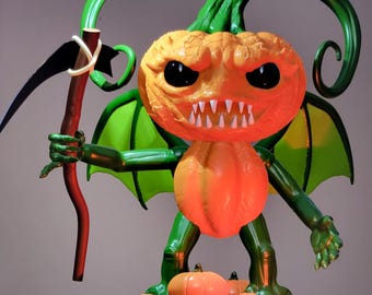 Puede incluir: Un monstruo de calabaza verde con alas y una guadaña. El monstruo está de pie sobre una base negra con tres calabazas más pequeñas.