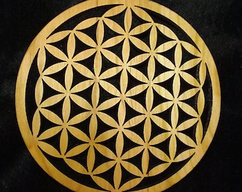 May include: A wooden round wall hanging with a geometric pattern of overlapping circles and flower shapes, known as the Flower of Life.