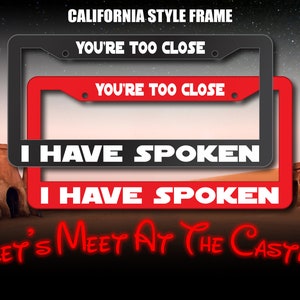 May include: A red and black California style license plate frame with the text "You're Too Close" and "I Have Spoken" in white letters. The frame is displayed against a desert background with the text "Let's Meet At The Castle" in red letters.