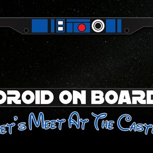 May include: A black license plate frame with a blue and red Star Wars themed design. The text "DROID ON BOARD" is printed in white on the bottom of the frame. The text "Let's Meet At The Castle" is printed in blue below the frame.