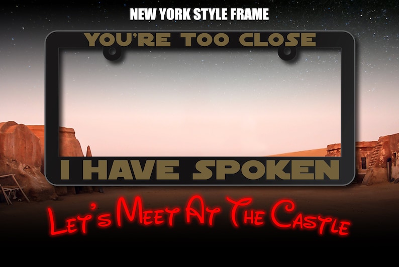 May include: A black license plate frame with gold text that reads "You're Too Close I Have Spoken" and red text that reads "Let's Meet At The Castle".