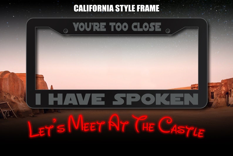 May include: A black metal license plate frame with the text "YOU'RE TOO CLOSE" and "I HAVE SPOKEN" in gray lettering. The text "LET'S MEET AT THE CASTLE" is in red lettering below the frame.
