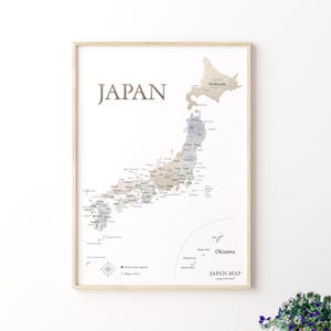 以下が含まれることがあります： 日本の地図の額入り。ベージュ、グレー、ブルーの落ち着いた色合いで、都道府県が詳細に描かれています。「JAPAN」の文字が上部に印刷されています。地図にはコンパスローズと「Japan Map」の文字が含まれています。