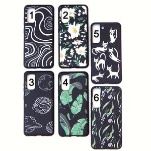 May include: A collection of six black phone cases with various designs. The designs include white swirls, white flowers, white cats, planets, green leaves, and purple and green foliage. The cases are rectangular with rounded corners.