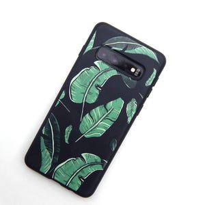 May include: Black phone case with a green and white banana leaf pattern. The case has a camera cutout and is designed to fit a smartphone. The leaves are detailed with white veins, creating a tropical aesthetic.