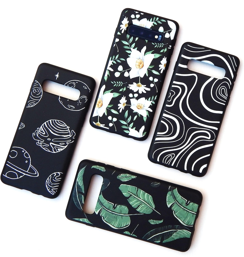 May include: Four black phone cases with unique designs. One case features white floral patterns, another has green leaves, a third displays white swirls, and the last showcases planets and stars in white. All cases have cutouts for the phone's camera and buttons.