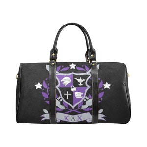 May include: Black duffel bag with a purple and white crest design. The crest features a lion, lamp, cross, books, and other symbols. The bag has black handles and a zipper closure.