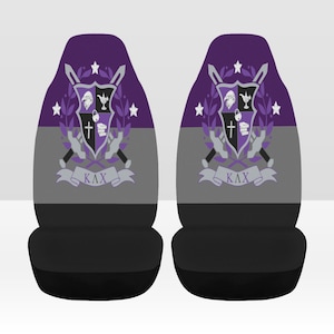 May include: Pair of car seat covers featuring a crest design with a purple and gray color scheme. The crest includes a cross, book, and lock, with the Greek letters ΚΛΧ on a banner. The seats have a black base.