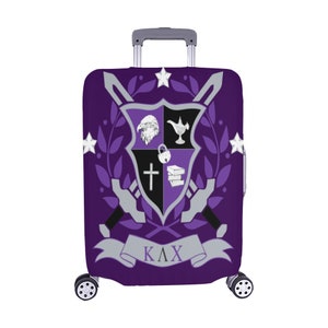 May include: Purple luggage cover with a black and white crest featuring a sword, eagle, lamp, padlock, cross, and books. The crest is surrounded by a laurel wreath and stars. The text "ΚΛΧ" is on a silver banner below the crest.