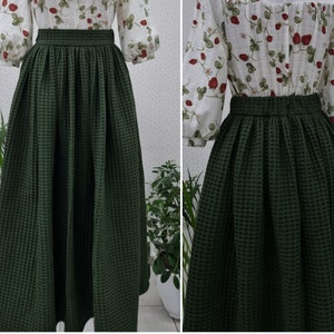 May include: A dark green waffle-textured skirt with a gathered waistband. The skirt is midi length and has a flowy silhouette.