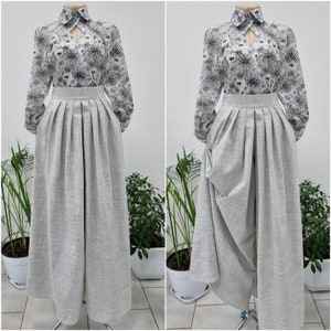May include: Two grey skirts with a floral print blouse. One skirt is pleated and the other is gathered with a draped design.