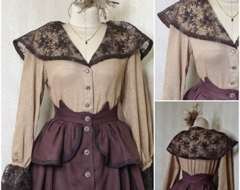 May include: A beige long-sleeved blouse with a dark brown lace collar and matching lace cuffs, paired with a dark brown skirt featuring a button-down front, a high waist, and a peplum detail. The blouse also features a button-down front closure.