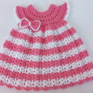 K&ouml;nnte beinhalten: Ein rosa-wei&szlig;es geh&auml;keltes Babykleid mit einer Schleife am Oberteil.
