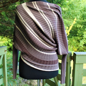 May include: A brown and white striped sweater with a draped design. The sweater is on a white mannequin and has long sleeves.