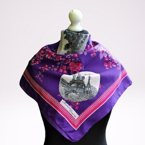 May include: Purple silk scarf with a pink floral pattern and a black and white image of a building with the text "Barcelona" printed on the bottom.