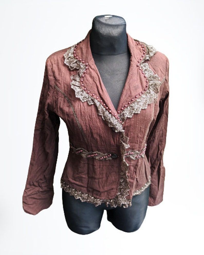 May include: A brown, long-sleeved, fitted jacket with lace trim and beaded accents.