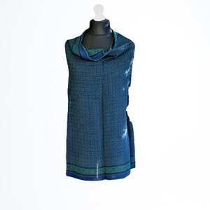 May include: A blue patterned scarf with a green and white geometric design. The scarf is displayed on a white mannequin.