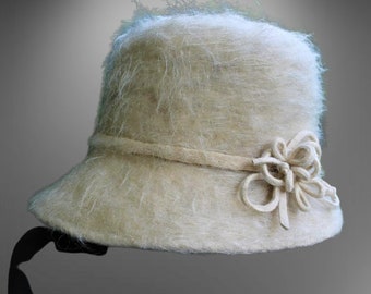 May include: A cream-colored, fuzzy felt hat with a wide brim and a decorative flower accent.