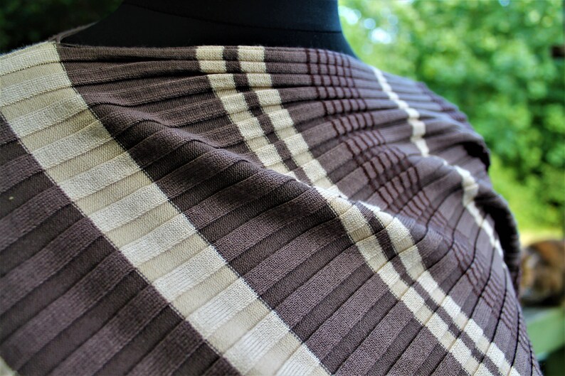 May include: Brown and white striped fabric with a ribbed texture. The fabric is folded and draped over a form.