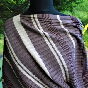 May include: A brown and white striped fabric with a textured, ribbed pattern. The fabric is draped over a mannequin.
