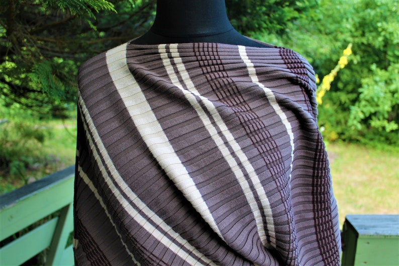 May include: A brown and white striped fabric with a textured, ribbed pattern. The fabric is draped over a mannequin.