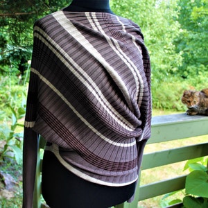 May include: A brown and white striped sweater with a twisted front detail. The sweater is on a mannequin and has long sleeves.