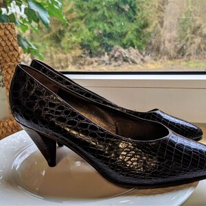 May include: A pair of brown leather pumps with a pointed toe and a low, angled heel. The shoes are on a white plate.
