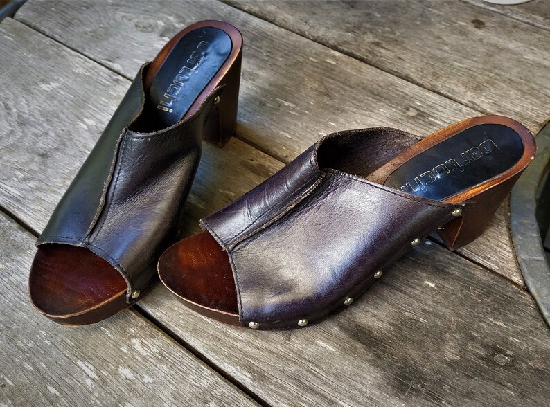 May include: Pair of brown leather heeled clogs with wooden platforms and silver studs. The clogs have a peep toe and are labelled "Lauren"