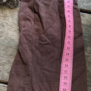 May include: A brown fabric sleeve with a lace trim. The sleeve is measured with a pink tape measure that reads from 36 to 65 inches.