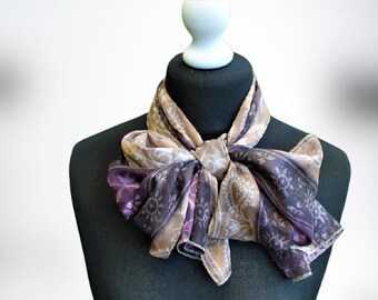 May include: A brown and purple patterned silk scarf tied in a bow around a black mannequin's neck.