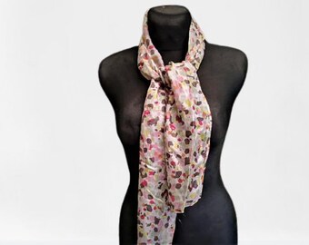 May include: A white silk scarf with a colourful abstract print. The scarf is tied around a black mannequin's neck.
