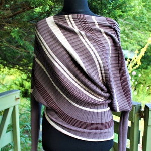 May include: A brown and white striped sweater with a draped design. The sweater is made of a soft, knit fabric.
