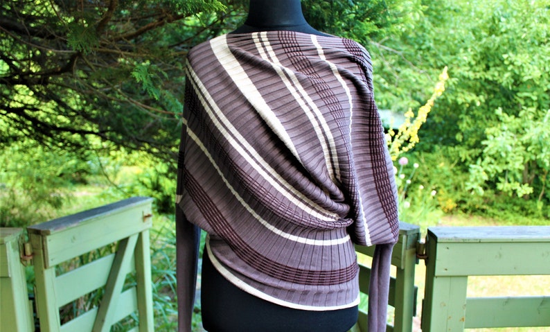 May include: A brown and white striped sweater with a draped design. The sweater is made of a soft, knit fabric.