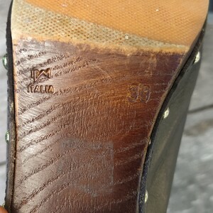 May include: Close-up of the bottom of a black leather shoe with a wooden sole. The sole is marked with "PM Italia" and the size "39".