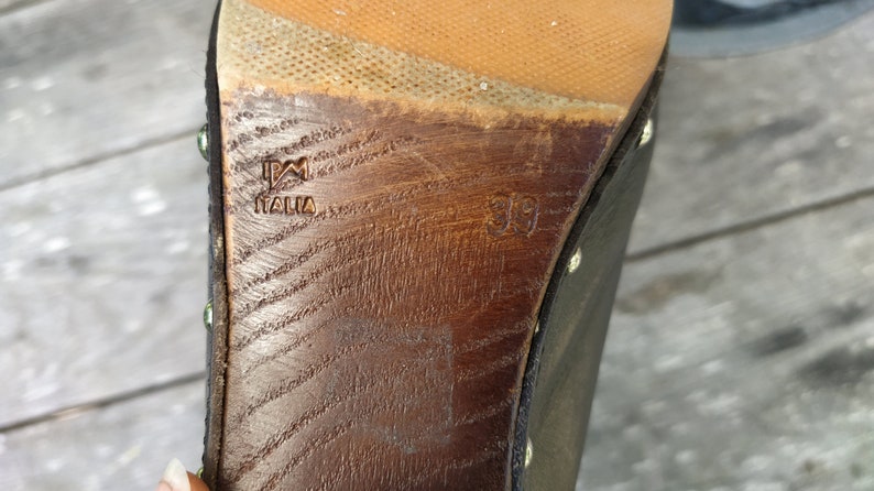 May include: Close-up of the bottom of a black leather shoe with a wooden sole. The sole is marked with "PM Italia" and the size "39".