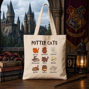 May include: A cream-coloured tote bag featuring the words "POTTER CATS" and cartoon cat illustrations inspired by Harry Potter characters. The bag is held up, with a Hogwarts castle and crest visible in the background.