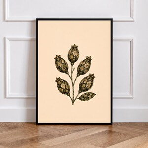 May include: A framed wall art print featuring a botanical illustration of a plant with five bulbous, textured seed pods and one leaf. The pods and leaf display a dark green and brown diamond-patterned texture against a solid light cream background.