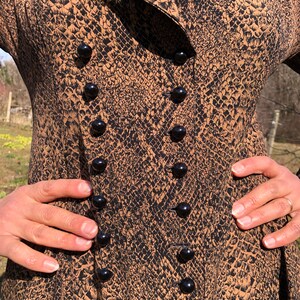 May include: A brown and black snakeskin print dress with a double row of black buttons down the front.