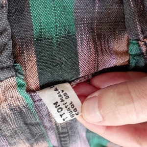 May include: A close-up of a fabric tag attached to a striped shirt. The tag is white with black text that reads "100% Cotton, Made in India, Size 1, 41"W x 29"L".