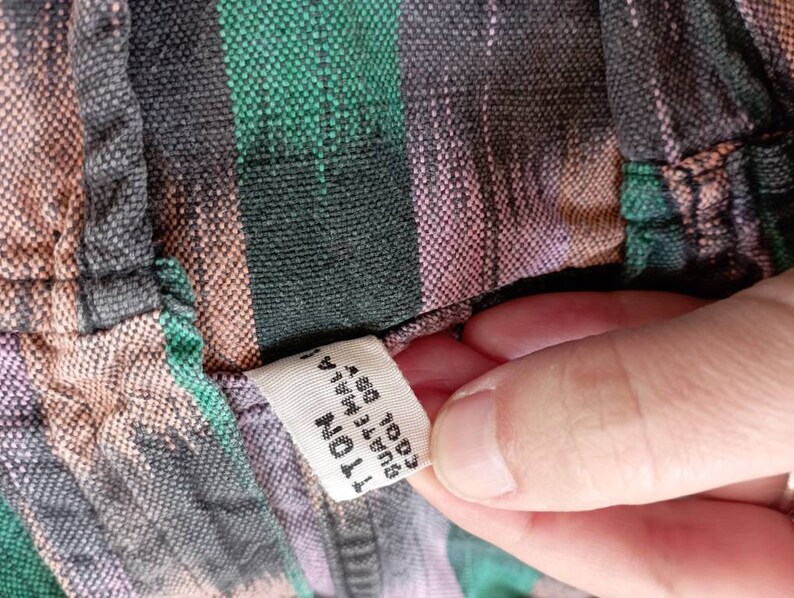 May include: A close-up of a fabric tag attached to a striped shirt. The tag is white with black text that reads "100% Cotton, Made in India, Size 1, 41"W x 29"L".