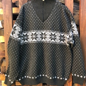 May include: A dark green sweater with a white snowflake pattern. The sweater has a high neck and a zip.