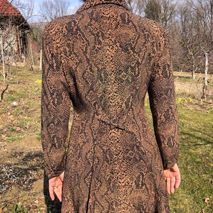 May include: A long-sleeved dress with a brown and black snake print pattern. The dress has a collared neckline and a long skirt.