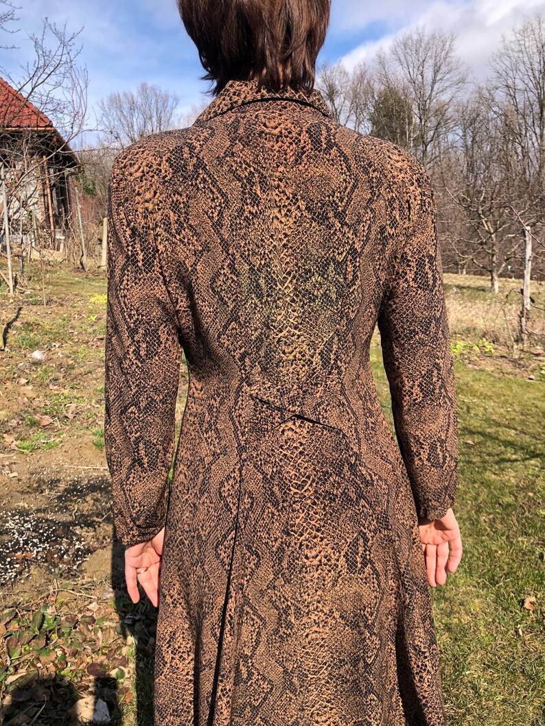 May include: A long-sleeved dress with a brown and black snake print pattern. The dress has a collared neckline and a long skirt.