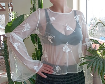 Blouse transparente en résille blanche des années 90 et 70, décorée de fleurs brodées à la machine. Taille M.